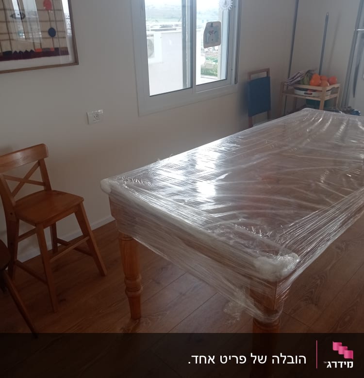 שולחן עטוף בניילון נצמד בחדר עם חלון פתוח